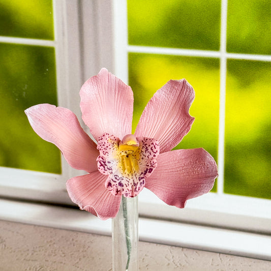 Mauve gumpaste orchid in a vase with a blurred green background