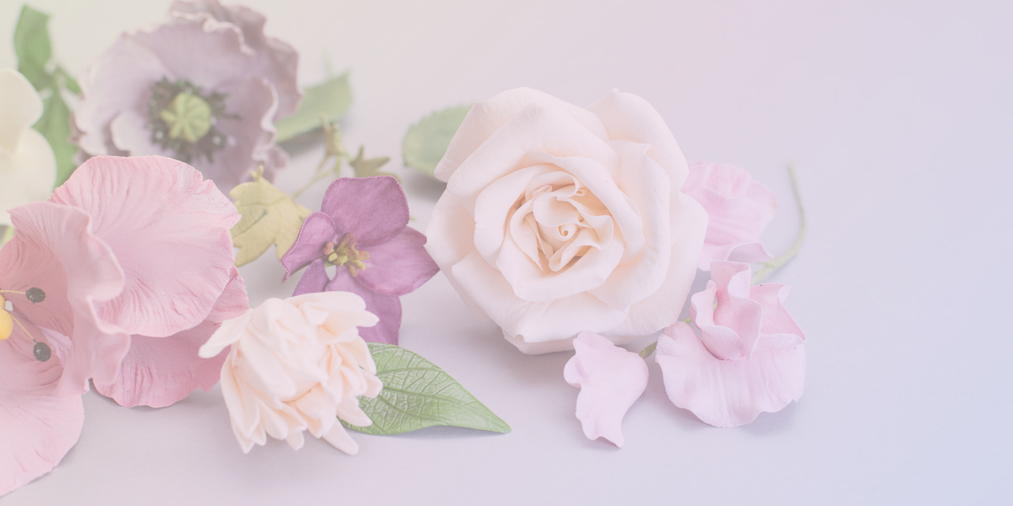 Pastel-colored sugar flowers on a light colorful gradient background